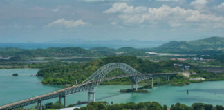 Aerial view of a bridge spanning over turquoise water surrounded by greenery