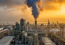 Drone Strike IGNITES UAE Energy Hub: Massive FIRE An industrial oil refinery with smoke billowing from a stack at sunset