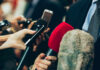 Journalists holding microphones at a press conference