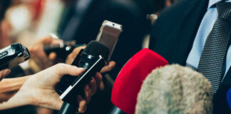 Journalists holding microphones at a press conference
