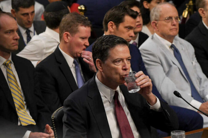 shutterstock_675303664.jpg A man in a suit drinking water during a congressional hearing