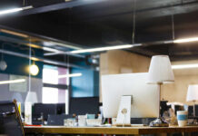 A modern office workspace featuring a computer, lamp, and decorative items on a desk