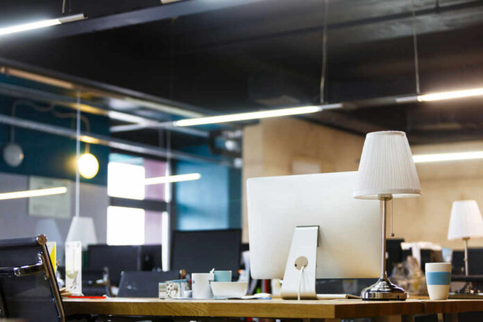 A modern office workspace featuring a computer, lamp, and decorative items on a desk