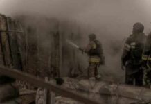 Firefighters spray water into a smoke-filled structure