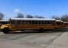 Yellow school buses parked in a lot under a blue sky