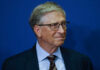 A business leader with glasses smiling in front of a blue background