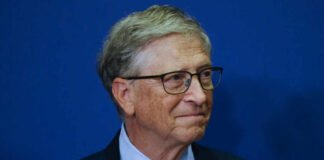 A business leader with glasses smiling in front of a blue background