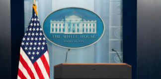 Podium with microphones in front of the White House seal and an American flag