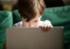Young boy intently focused on a laptop in a cozy setting