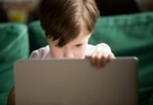 Young boy intently focused on a laptop in a cozy setting