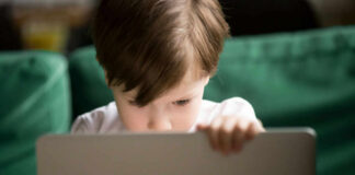 Young boy intently focused on a laptop in a cozy setting