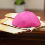 A pink ceremonial cap placed on a decorative cloth