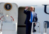 A political figure waving from the steps of an aircraft