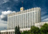 Russia’s Wallet Screams, War Grinds On Government building with a Russian flag under a cloudy sky