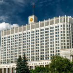 Russia’s Wallet Screams, War Grinds On Government building with a Russian flag under a cloudy sky