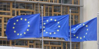 Three European Union flags waving in front of a building