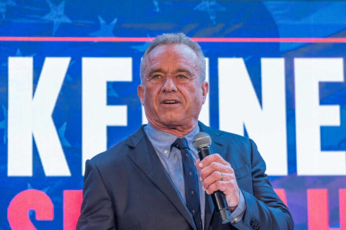 Man in a suit speaking into a microphone at a political event