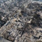 Aerial view of a neighborhood devastated by wildfire, showing burned structures and debris