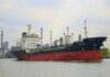 A cargo ship navigating through an industrial harbor