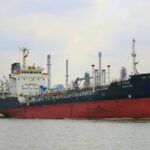 A cargo ship navigating through an industrial harbor