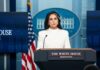 Woman in white suit speaking at White House press podium