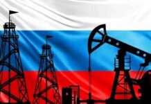 Oil pumpjack and drilling rigs silhouetted against the Russian flag