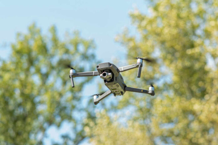 shutterstock2509865523jpg A drone flying against a backdrop of green trees and a blue sky