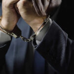 Close-up of a mans hands in handcuffs wearing a suit