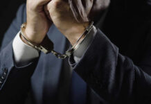 Close-up of a mans hands in handcuffs wearing a suit