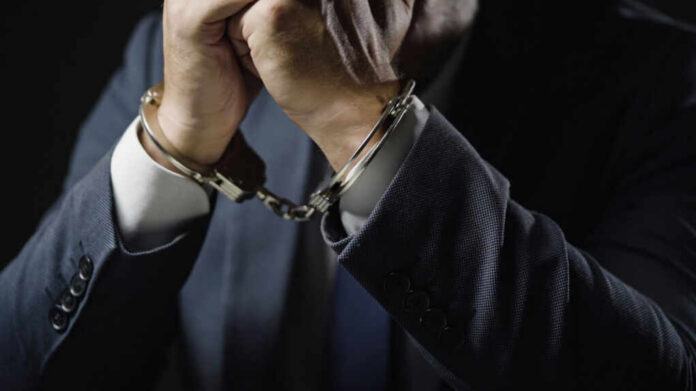 Close-up of a mans hands in handcuffs wearing a suit