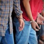 Handcuffed people standing in a line