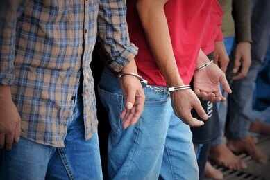 Handcuffed people standing in a line