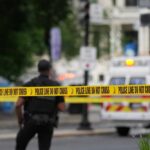 Police officers near a crime scene marked by caution tape