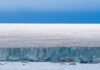 Ice cliff along a polar glacier under a blue sky