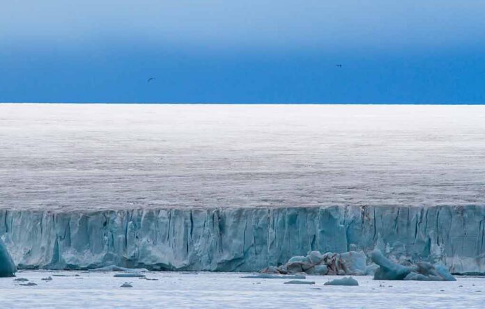 Ice cliff along a polar glacier under a blue sky