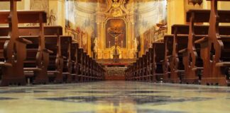 Church interior with wooden pews facing ornate altar