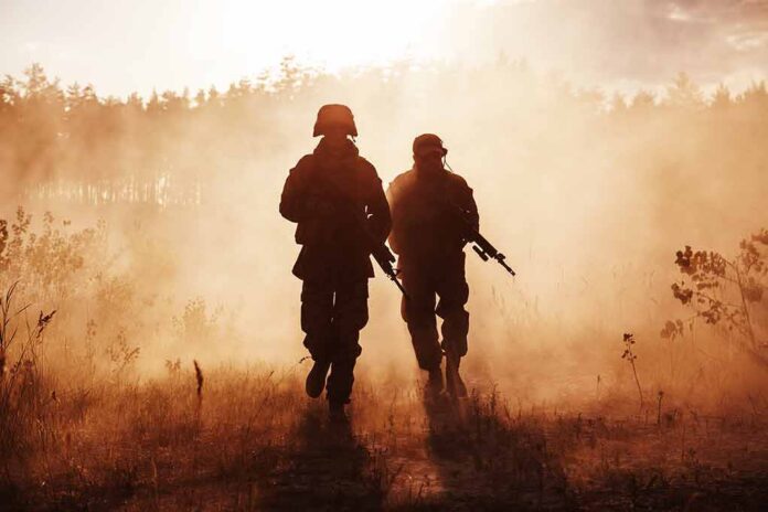 Two soldiers walking through a smoky field at sunset