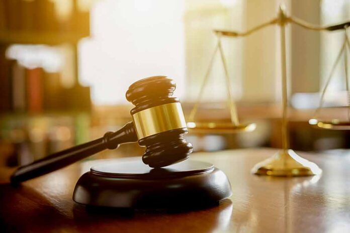 Judge's gavel on a block with scales of justice in the background