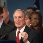 older man in suit speaking at a podium