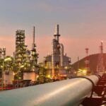 Energy War Countdown Jolts D.C. Oil refinery with pipelines at sunset