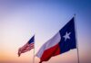 Texas and United States flags waving at sunset