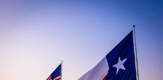 Texas and United States flags waving at sunset