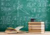 Stack of books with graduation cap in front of chalkboard with math formulas