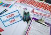 Voter registration table with forms, pens, and informational materials