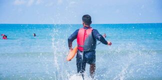 lifeguard wading into ocean with rescue buoy
