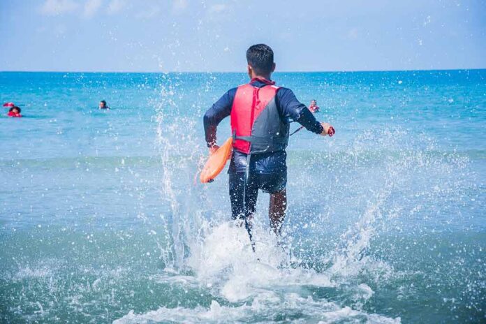 shutterstock_633531671-1 lifeguard wading into ocean with rescue buoy