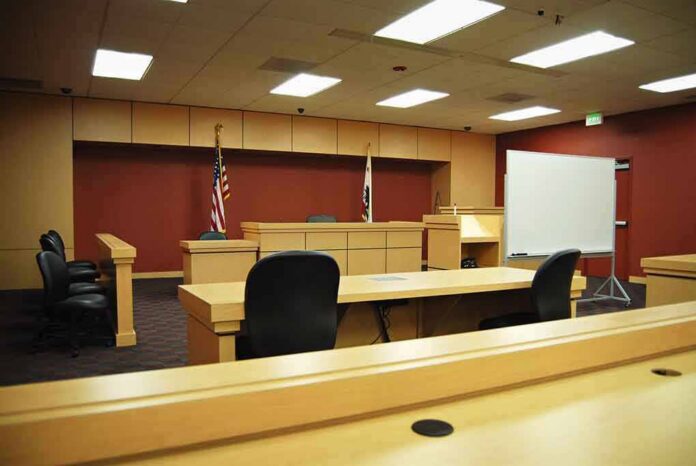 Interior view of an empty courtroom with wooden furniture and American flags