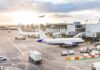 Airplanes at airport gates during sunset with ground vehicles and jet bridges