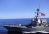 Hormuz Flashpoint: U.S. Hits Iranian Launchers Naval destroyer sailing on open sea with flag flying