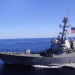 Hormuz Flashpoint: U.S. Hits Iranian Launchers Naval destroyer sailing on open sea with flag flying